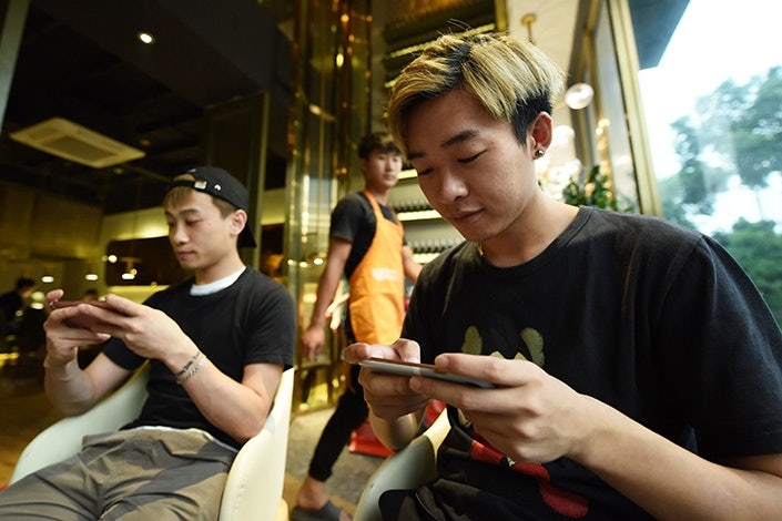Two Chinese gamers playing mobile phenomenon Honor of Kings. Photo: Caixin Global