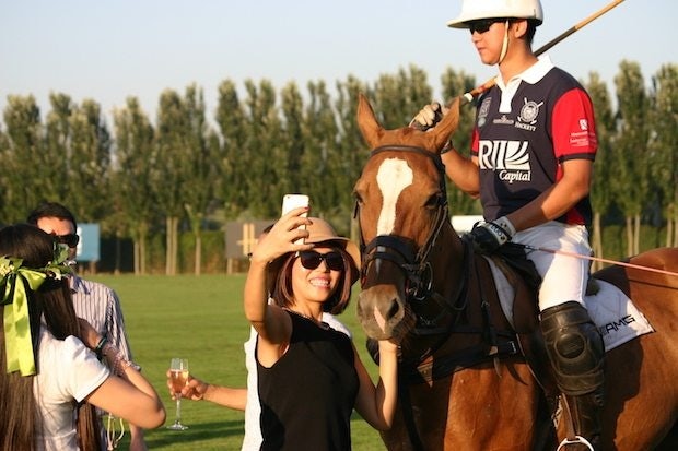 A woman snaps a selfie at British Polo Day in Beijing. (Jing Daily)