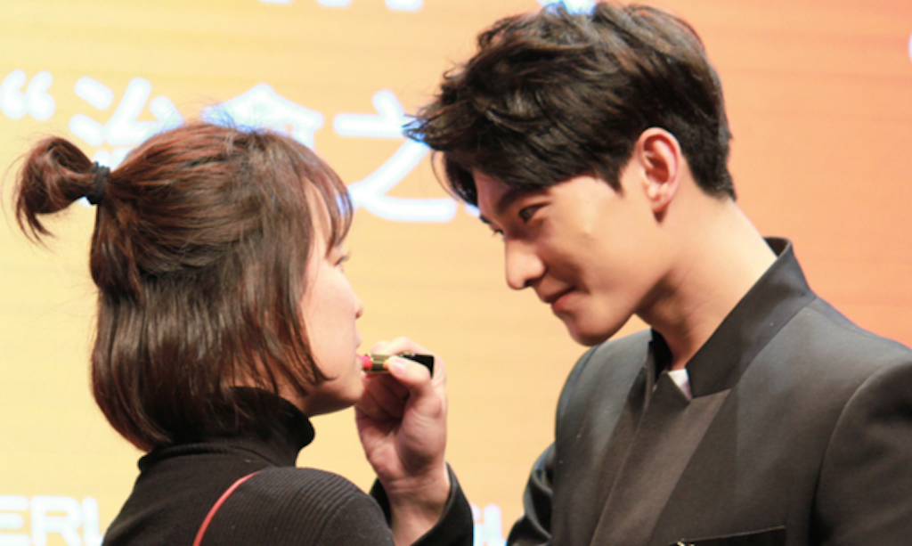 Yang Yang puts lipstick on one of his fans. Image via Sohu Fashion.