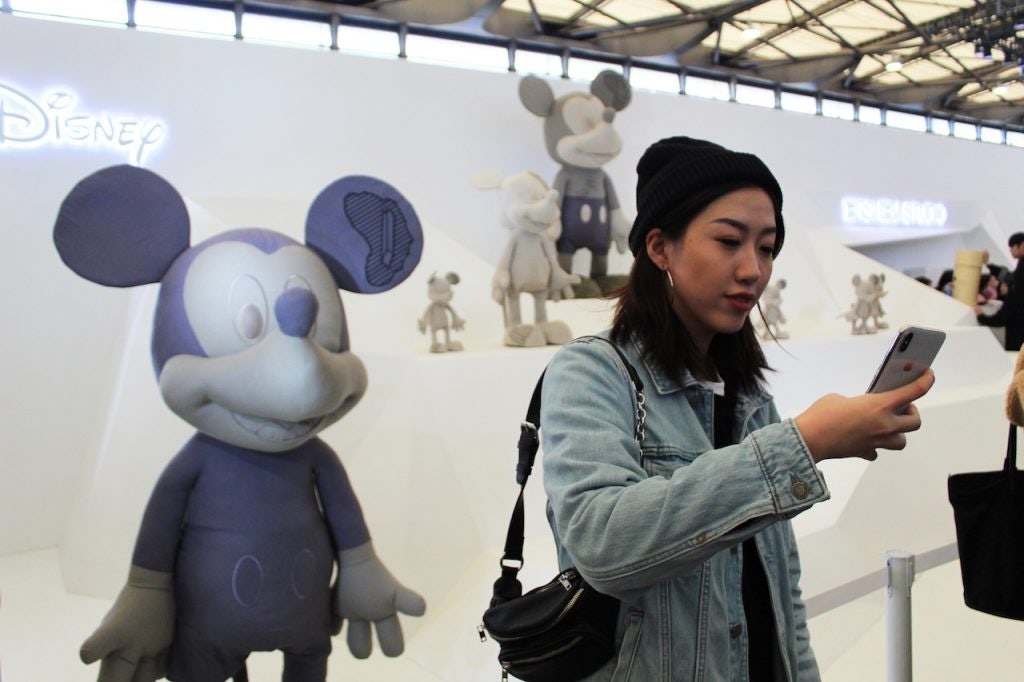 A fan taking a selfie with artist Daniel Arsham's Mickey Mouse. Photo: Ruonan Zheng/Jing Daily